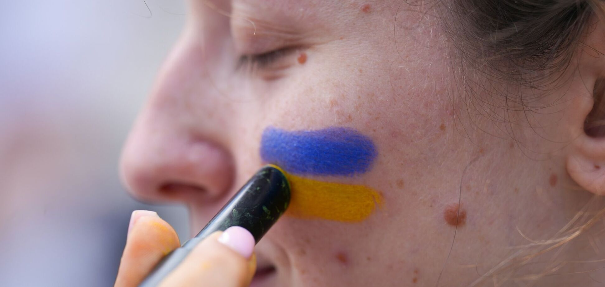 Ілюстрація – жінці наносять на обличчя кольори прапору України